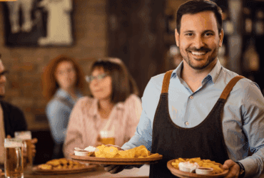 Smiling restaurant server delivering food to happy guests in a casual dining setting, representing improved customer experience with Applova’s email marketing tools.