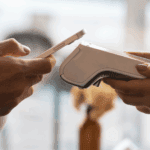Customer making a contactless payment using a smartphone at a restaurant counter with a handheld POS device.