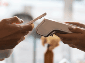 Customer making a contactless payment using a smartphone at a restaurant counter with a handheld POS device.