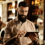 Restaurant owner using a tablet with a POS system behind the counter