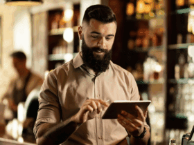 Restaurant owner using a tablet with a POS system behind the counter
