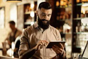 Restaurant owner using a tablet with a POS system behind the counter