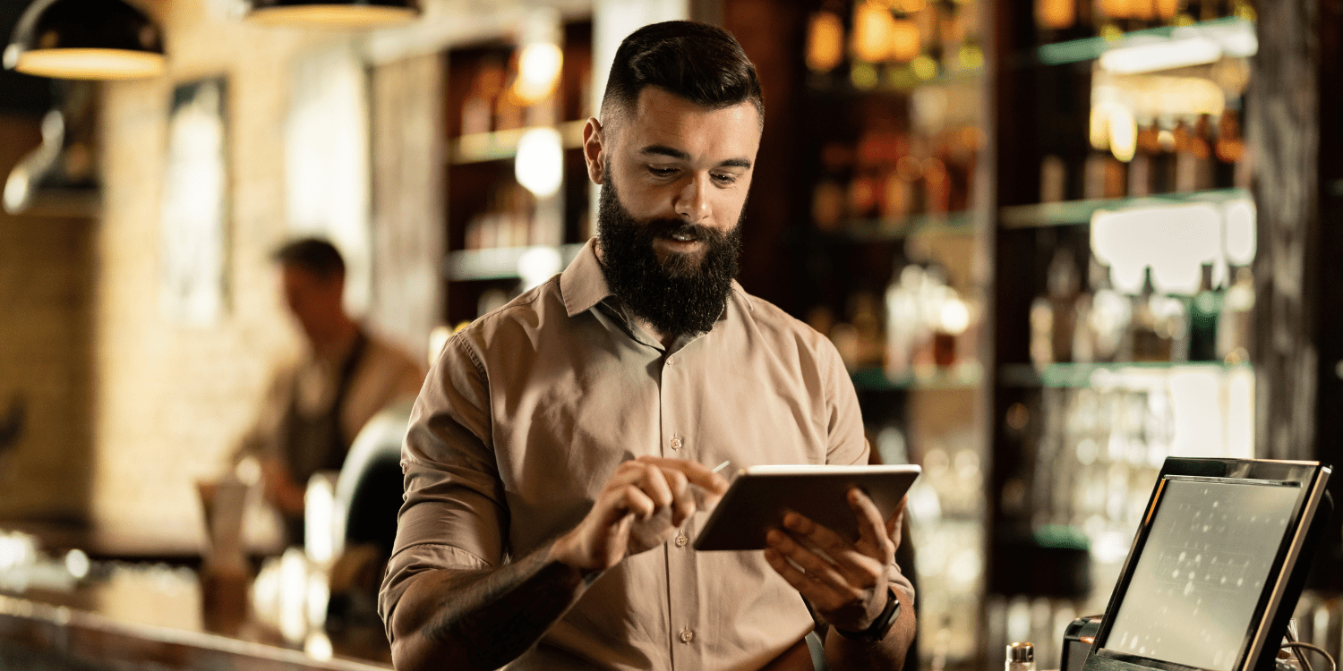Restaurant owner using a tablet with a POS system behind the counter